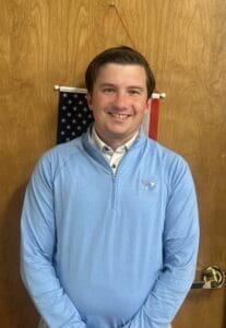 Smiling man in light blue pullover with flag